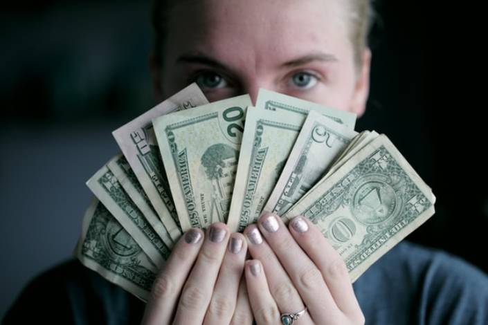 house sitter holding saved money in front of their face